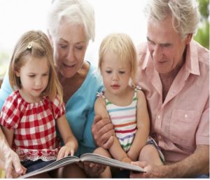 coppia di nonni che leggono un libro ai due nipotini